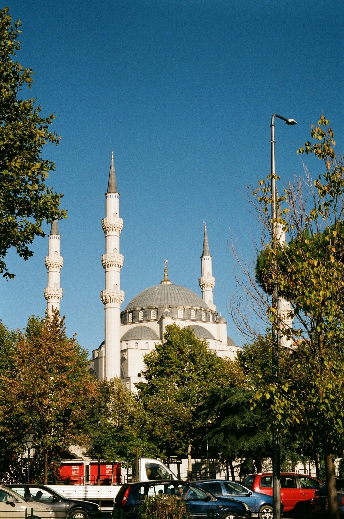 A mosque framed by trees and busy streets in central Tirana
