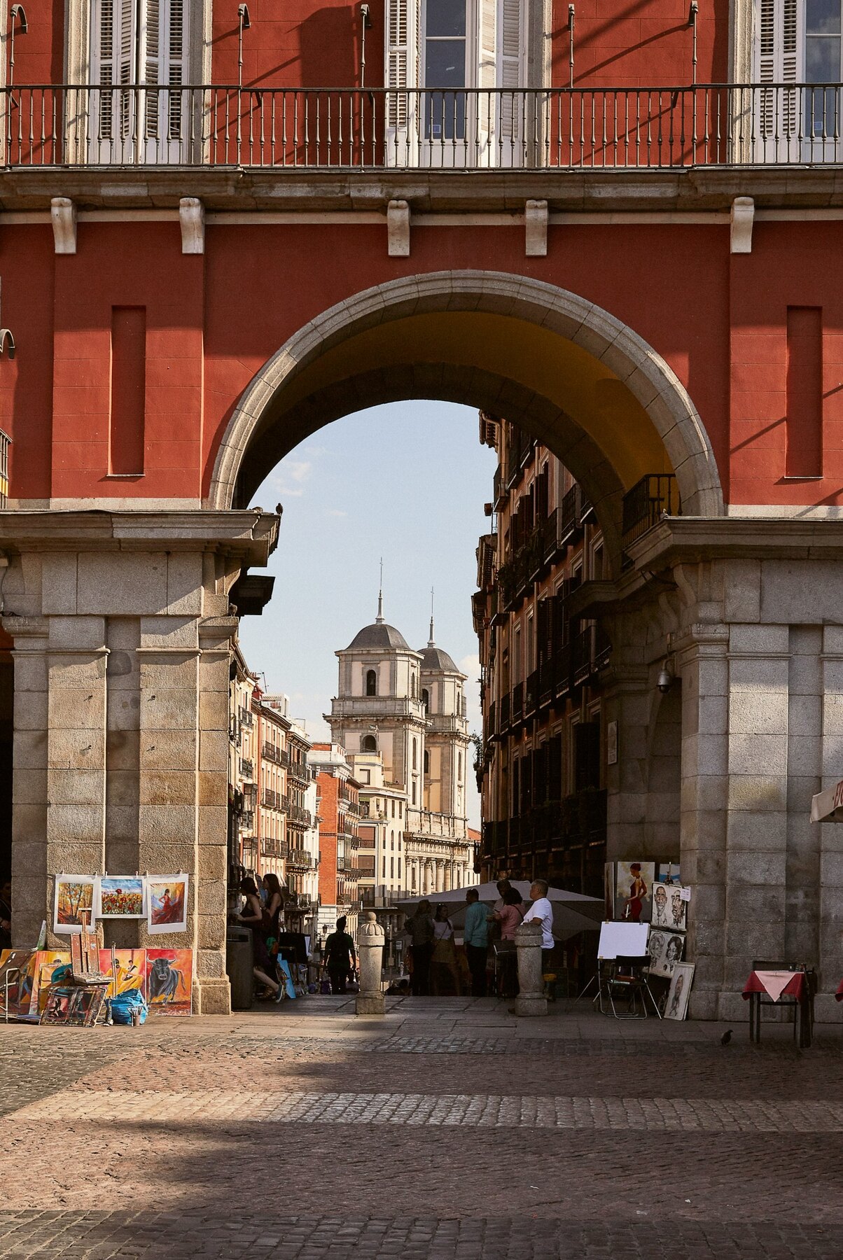 A Madrid street framed by a monumental arch and historic buildings
