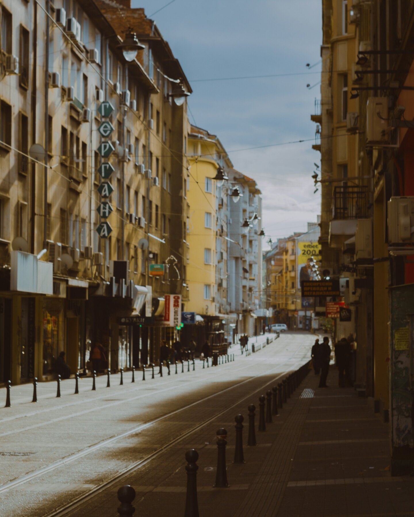 A quiet tram-lined street between layered city-centre buildings in Sofia