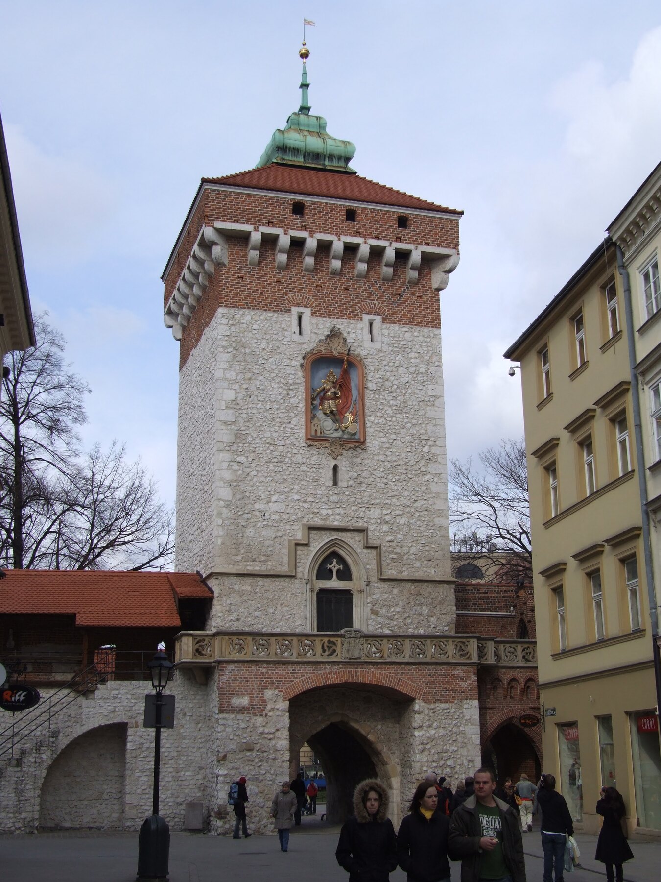 People passing beneath a historic city gate in Kraków
