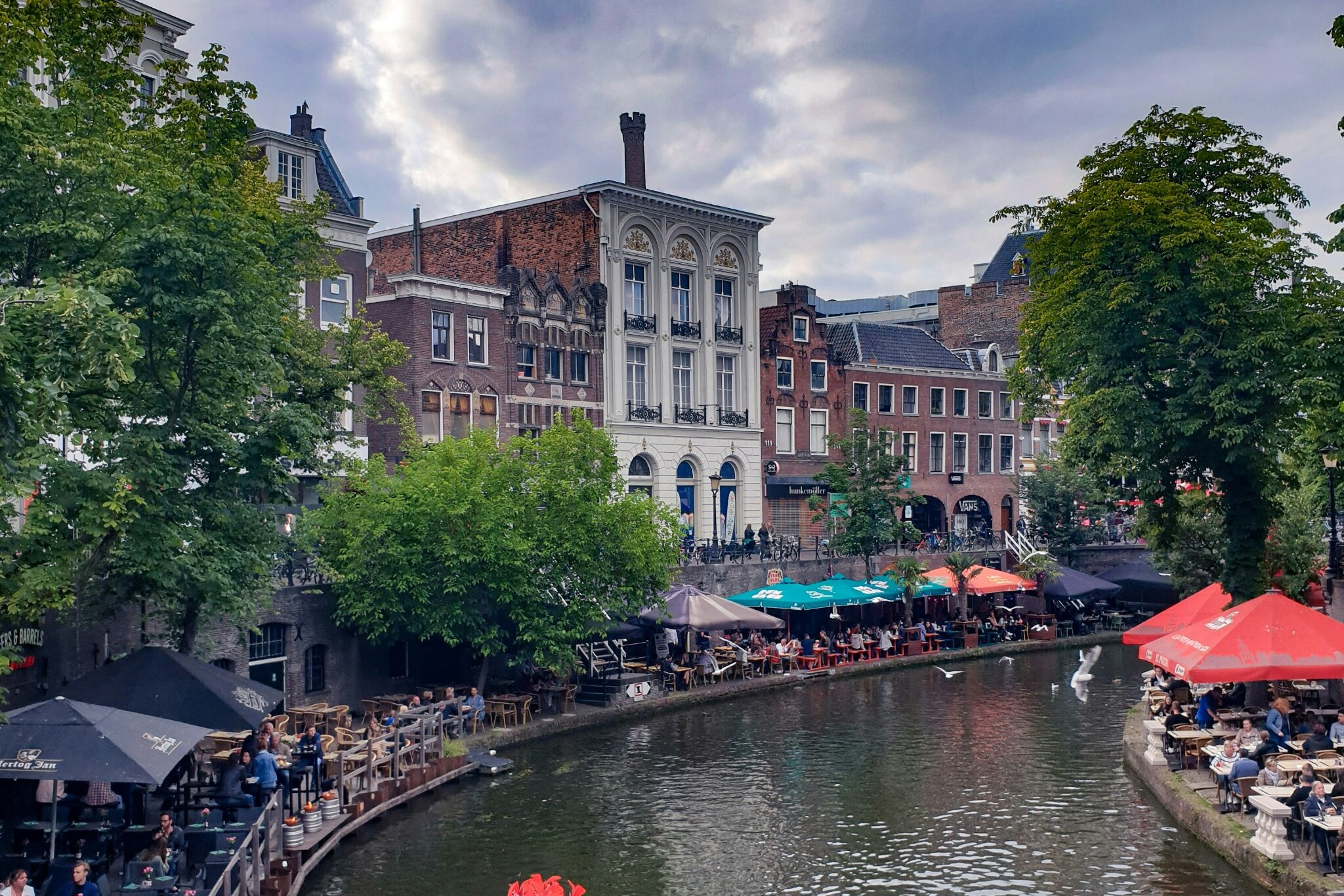Flowers and busy waterside terraces along an Utrecht canal