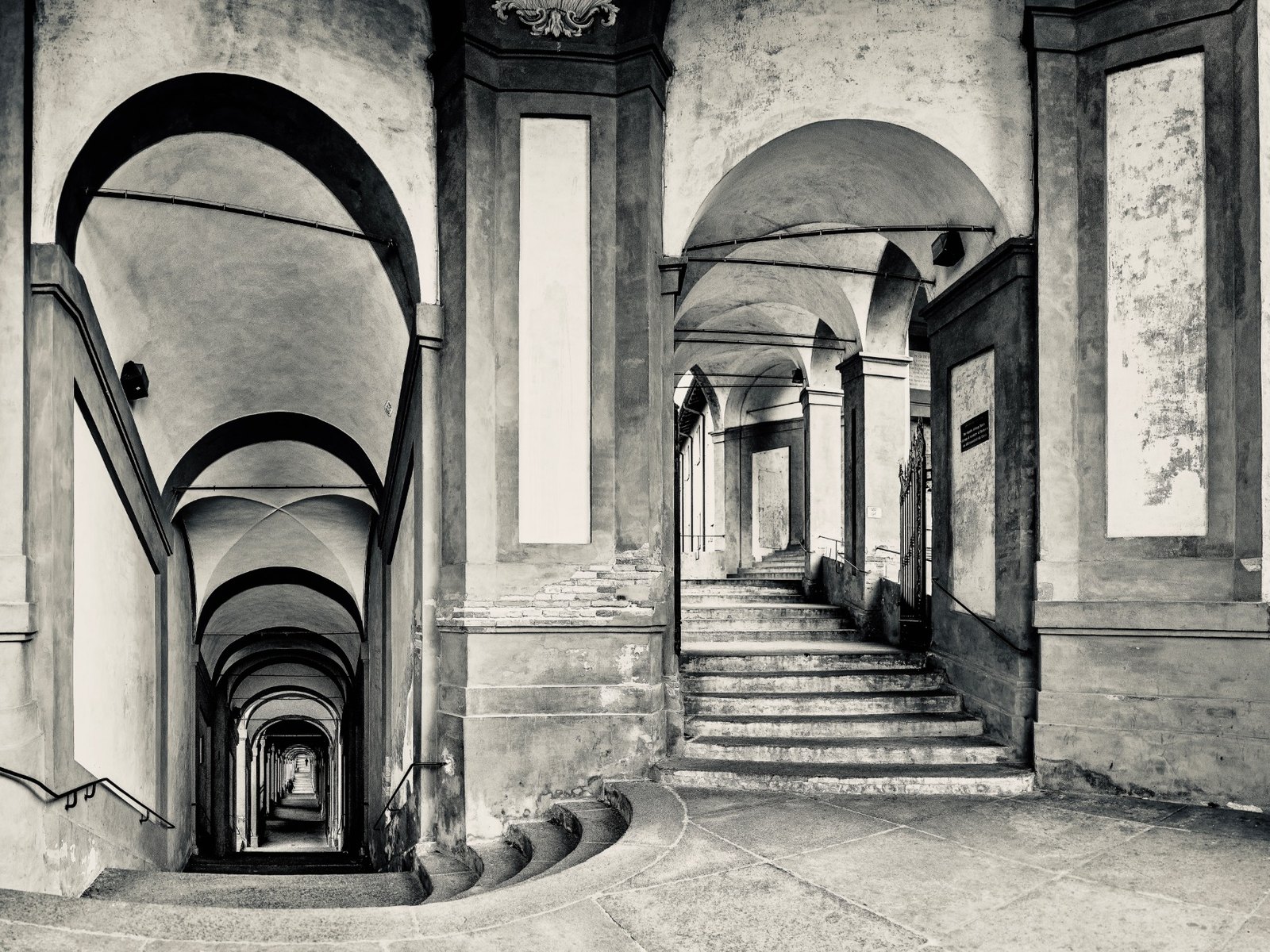 The long arcaded Portico di San Luca in Bologna, with stone steps and repeating arches.